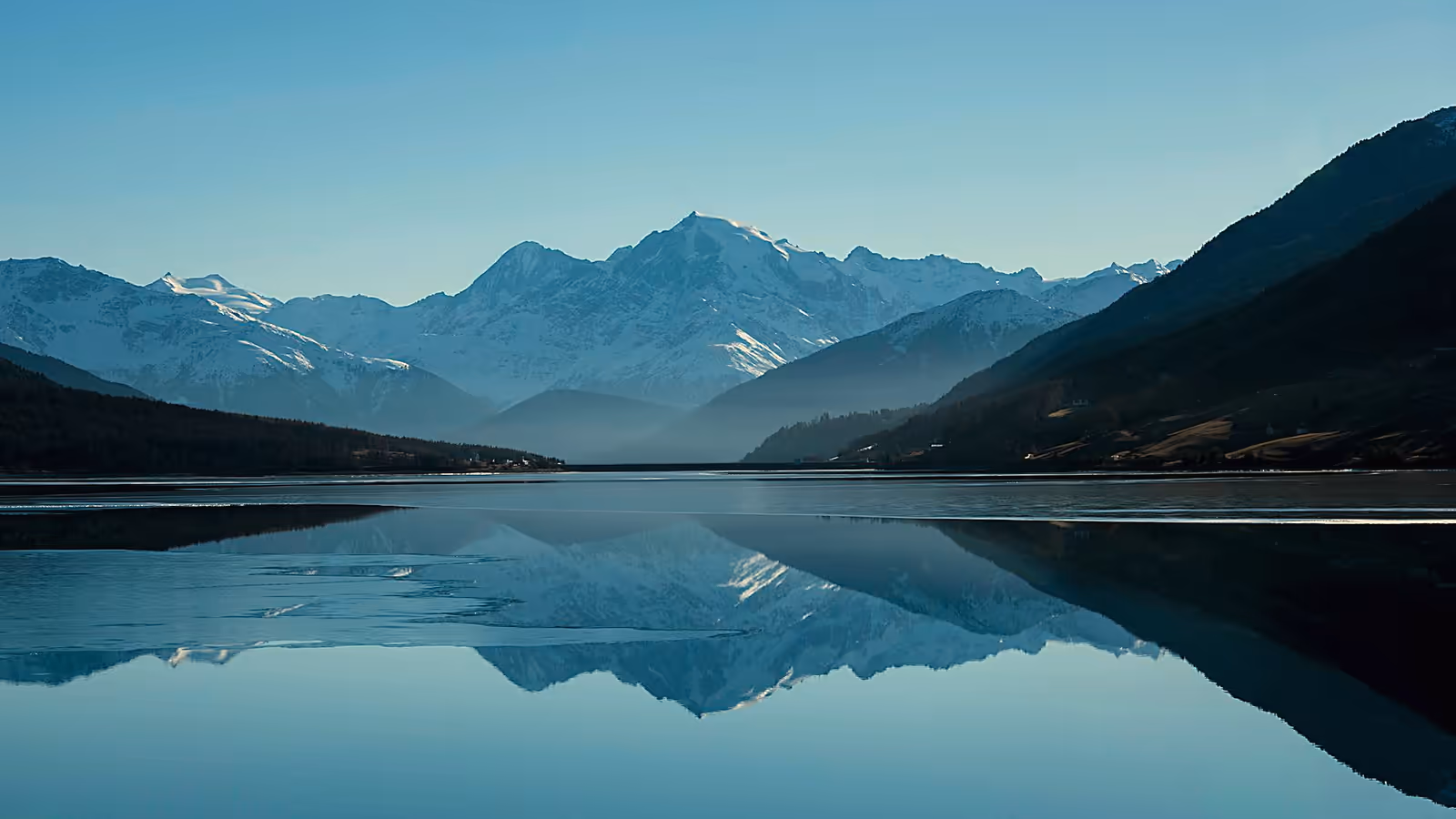 Snow capped mountains reflected in a calm alpine lake